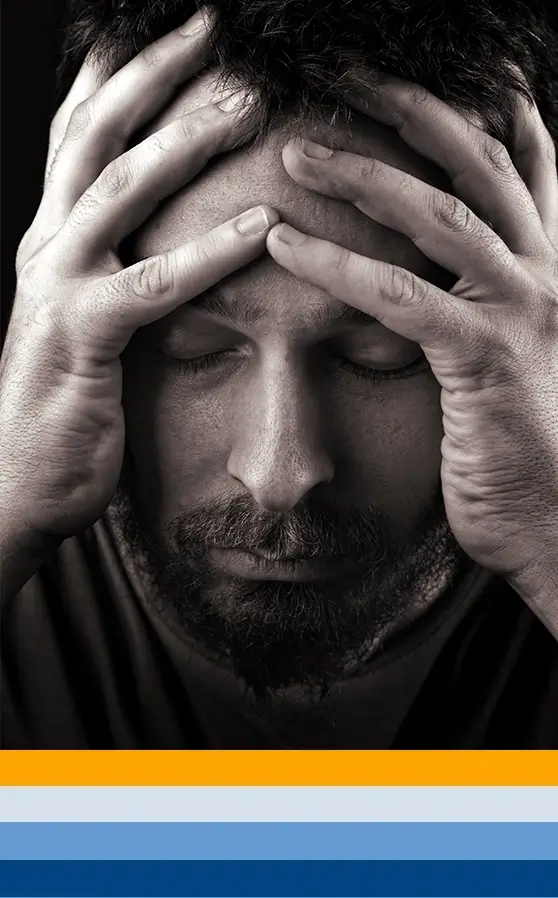 A man looking downwards, clutching his head, exemplifies the visual representation of anxiety.