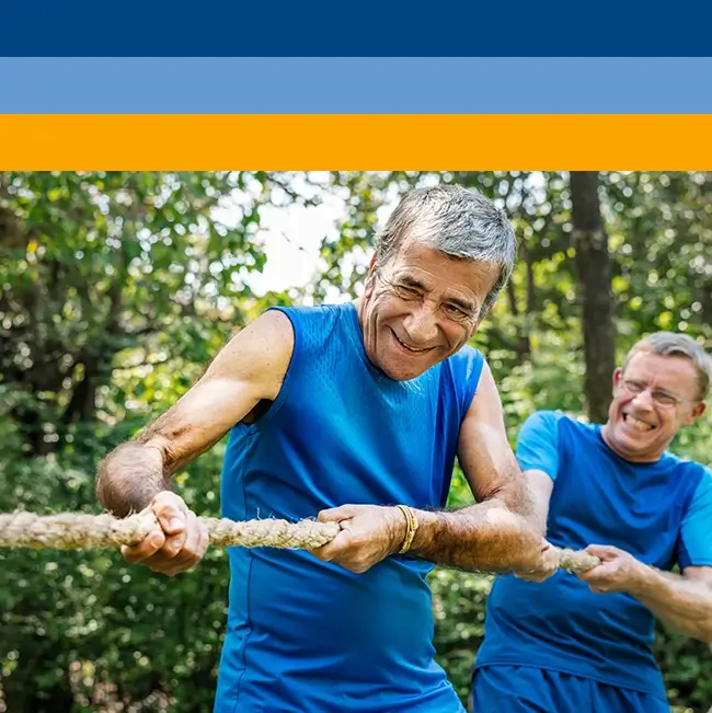 Two elderly gentlemen in blue t-shirts participating in a tug-of-war, highlighting that the desire for optimal mental wellness knows no age bounds