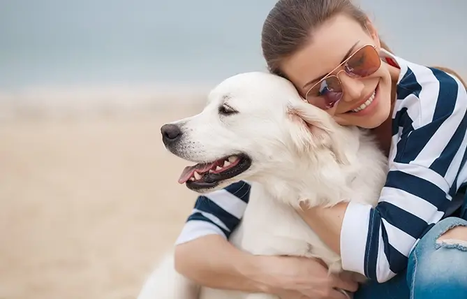 Woman smiling and hugging a yellow lab to show happiness when one takes control of their mental wellness