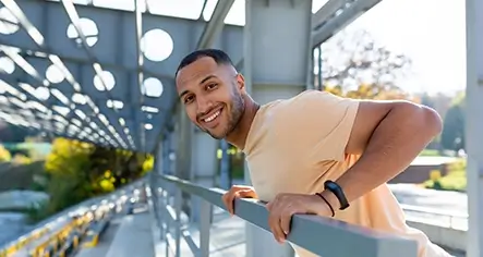 A man smiles while gazing out from a balcony, signifying the possibility of mental health recovery and finding happiness