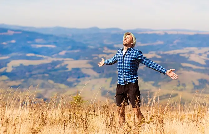 A man in nature, arms outstretched in joy, illustrating the sense of fulfillment this landscape can offer
