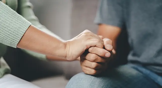 A close-up of a woman holding a man's hand in a gesture of support exemplifies the genuine care and concern that the BTC team extends to their patients.