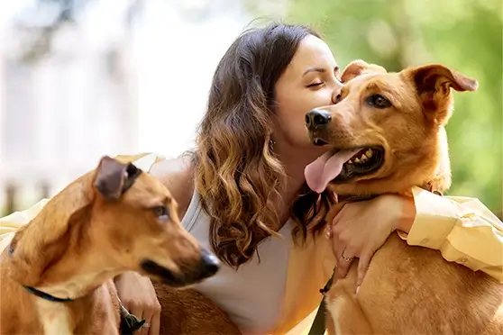 A smiling woman accompanied by two joyful dogs illustrates the vibrancy of a fulfilling life achievable through effective mental health treatment.